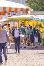 A busy outdoor market with lots of people and colourful stalls under parasols, Sindelfingen,