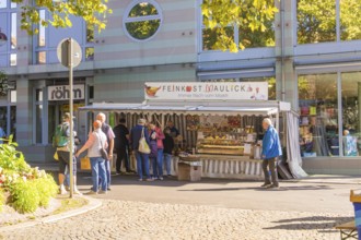 People standing in front of a delicatessen stall surrounded by modern architecture in the city