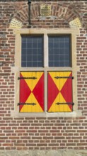 Window with red and yellow shutters on a brick wall, Raesfeld Castle, Münsterland, North
