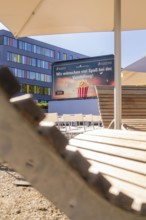 Chairs and screen under parasols with wooden details in a summery setting, open air cinema