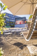 Seating and screen under parasols, sunny urban outdoor area, open air cinema Sindelfingen, district