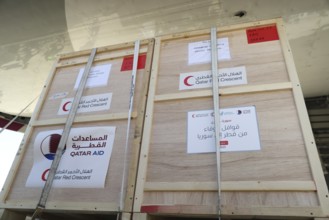 Relief workers unload boxes of medical aid provided by Qatar at Damascus International Airport,
