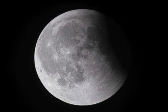 After a total lunar eclipse, the moon appears shortly after its rise in the evening sky as a