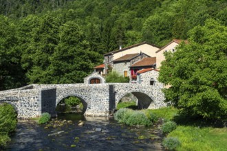 Stone bridge over the Pavin couze river flowing through the village of Saurier, Puy de Dome.