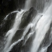 Vaucoux waterfall cascades gracefully over dark rocks, surrounded by lush greenery, Auvergne