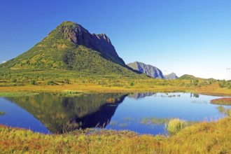 Mountain landscape with lake reflecting the surrounding greenery and clear blue sky, autumn,
