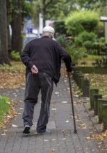 Elderly man going for a walk with the help of a walking stick, North Rhine-Westphalia, Germany