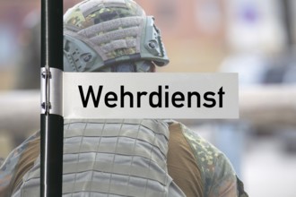 (Photomontage) Sign with text WEHRDIENST in front of a soldier
