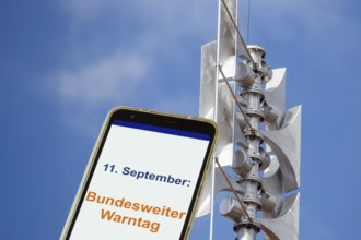 (Photomontage) Close-up of a siren, next to it an open smartphone with text 11 SEPTEMBER: FEDERAL