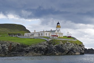 A lighthouse stands on a grassy cliff on a cloudy day, Robert Louis Stevensen, Isle of Noss,