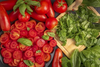 Fresh tomatoes and basil leaves on a chopping board, in bright red and green colours