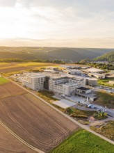 Large building in a rural setting with fields and rolling hills at dusk, new hospital building,