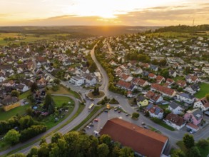 Sea of houses with curved streets in warm sunset light and green surroundings, small town of Perle