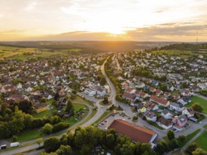 Urban landscape with houses and streets in gentle evening sun, surrounded by hills, small town