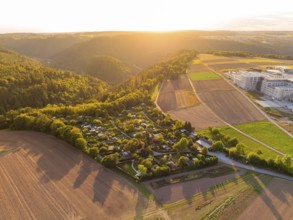 Campsite on the edge of a forest with farmland in the warm light of the setting sun, small town of
