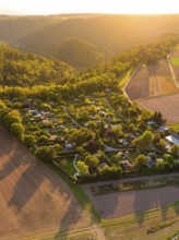 CampsiteIdyllic village landscape with fields and forest in the evening sun, surrounded by rolling
