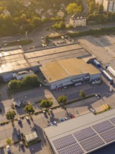 Industrial buildings at dusk with solar panels on the roof and car parks, small town of Perle