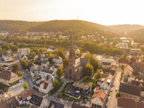 Small town with central church and surrounding hills seen from above in the warm evening light,