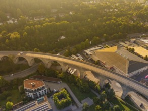 Viaduct in the evening light, passing through an urban and wooded landscape and illuminated at