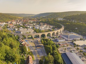 Large viaduct leading over a town and through a hilly landscape, shown from the air, small town of