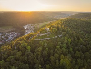 Historic castle ruins surrounded by woods on a hill, illuminated by the last light of the evening,