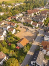Aerial view of a residential area with building site and surrounding natural areas, small town of