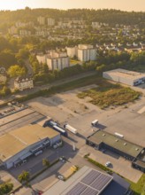 Industrial and residential area at dusk with surrounding nature and urban development, small town