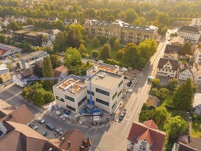 New building in a residential area with crane, surrounded by autumnal colours and streets, small