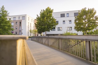 Modern residential buildings and trees flanking a bridge in the evening sun, small town of Perle