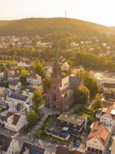 Church in the centre of a small town with a hill in the background, warm golden light envelops the