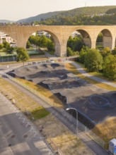 A pump track with asphalt and blue lines under a bridge in a green urban landscape, pump track,