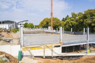 Construction site with concrete and metal structures, workers in construction clothing surrounded
