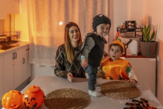 Mother and children enjoying halloween costumes, playing and laughing together in the cozy kitchen,