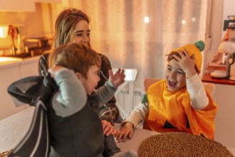 Mother and children wearing halloween costumes, playing and laughing at home in the kitchen