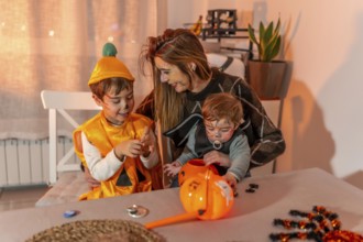 Mother and children with painted faces wearing halloween costumes are playing at home with pumpkin
