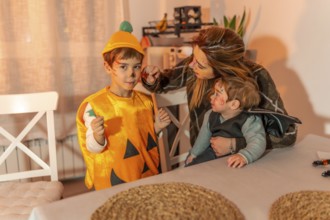 Mother painting her children's faces with halloween makeup, preparing for trick or treating