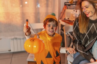 Happy child wearing pumpkin costume holding a plastic jack o' lantern celebrating halloween with