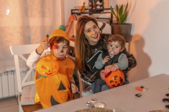 Mother and children with painted faces are smiling and holding pumpkin buckets, celebrating
