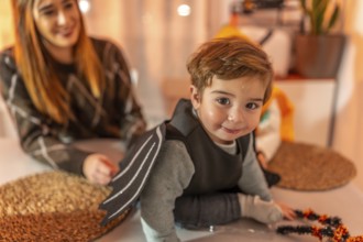 Smiling toddler wearing a bat costume crawling on a table while getting ready for a halloween party