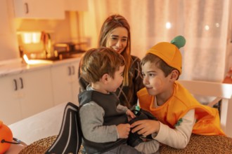 Two young brothers wearing halloween costumes playing together at home, watched by their smiling