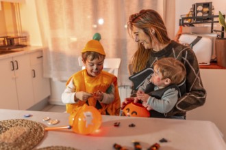 Mother and children wearing halloween costumes are sitting at the kitchen table and preparing for