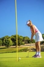Professional golfer concentrating on the green, about to putt during a sunny day on a beautiful