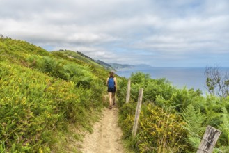 Female tourist enjoying a picturesque hike along the cliffs leading to sakoneta beach in zumaia,