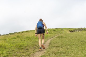 Female tourist walking up the grassy hill at sakoneta beach near zumaia in the basque country,