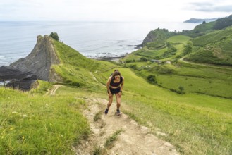 Tired athlete taking a break during trail running workout along the picturesque cliffs of zumaia,