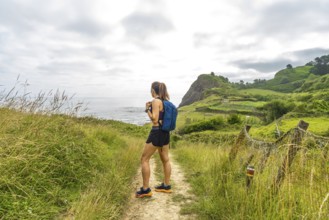 Female hiker enjoying the scenic view of sakoneta beach and its flysch cliffs in zumaia, gipuzkoa,