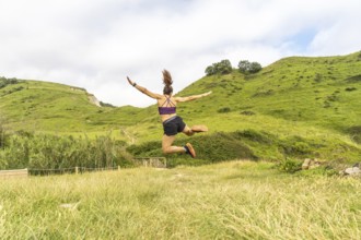 Sporty woman jumping with outstretched arms in a beautiful natural landscape in zumaia, gipuzkoa,