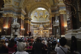 Tourists and locals are attending a mass in st. Stephen's basilica, a romanesque catholic basilica
