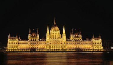 Majestic hungarian parliament building glowing gold at night, reflected in the danube river,