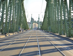 Tourists walking on liberty bridge in budapest, hungary, on a sunny day, with its iconic green